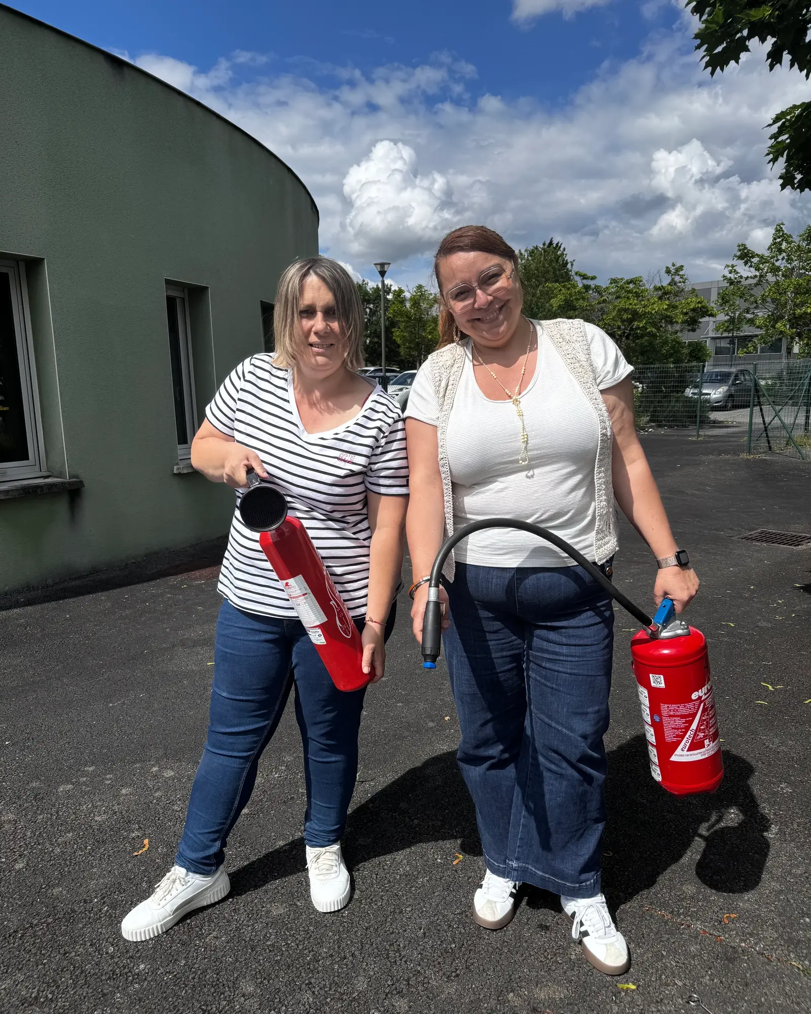 Deux participantes souriantes pendant l’exercice de manipulation des extincteurs